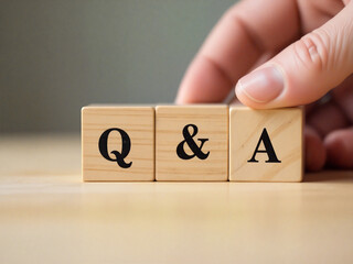 Q and a concept is being created with wooden cubes by human hand