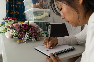 Florist drawing sketches of flower arrangements in notebook
