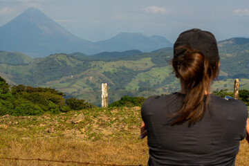 Tourist admiring the landscape with Arenal Volcano in the background, during a sunny day in Costa...