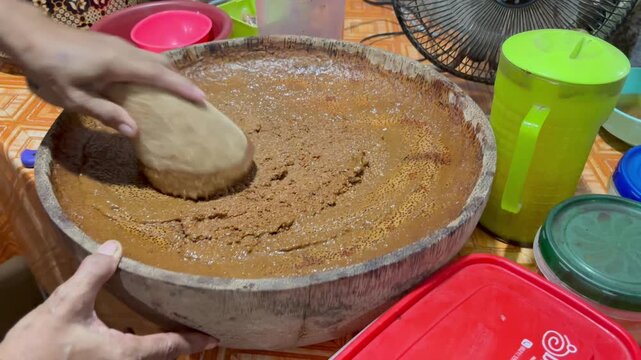 The process of making "pecel" seasoning from ground peanuts.