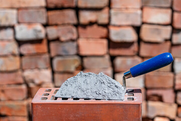 Dry cement or mortar. Cement powder and trowel on red brick at construction site, closeup
