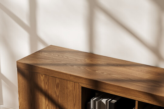 Wooden storage cabinet mockup in modern interior with natural sunlight casting shadows on white wall surface. 3D Rendering