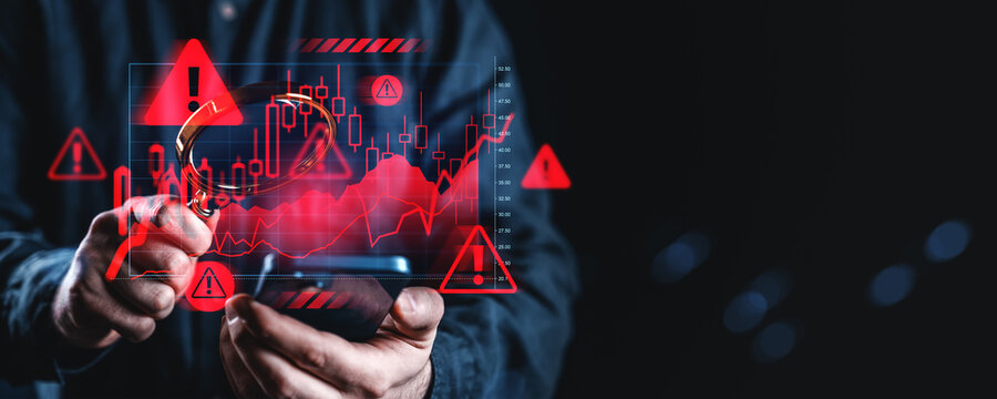 Financial fraud detection concept with man holding magnifying glass over digital chart full of red warning signs and analytics on dark background.