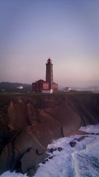 Vertical, aerial footage of Penedo da Saudade Lighthouse at sunset in Marinha Grande, Portugal