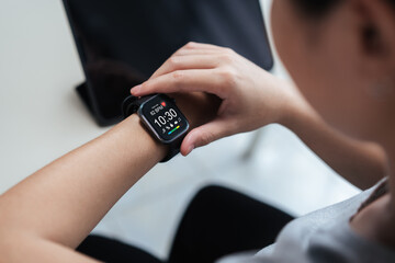 Close-up of a person checking a smartwatch with heart rate and time display, showing everyday...