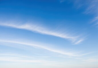 Obraz premium Wispy white clouds drift across a vast, clear blue sky on a bright, serene day, evoking a sense of peace and openness