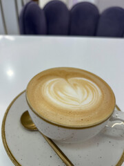A beautifully crafted cup of coffee with intricate latte art rests on a stylish plate next to a...