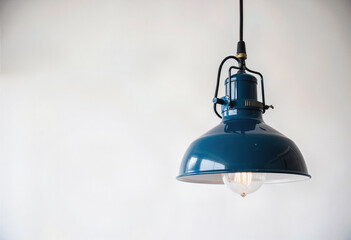 A close-up of a modern industrial-style pendant light with a blue enamel shade and an exposed filament bulb, creating a chic and retro vibe for interior design. 