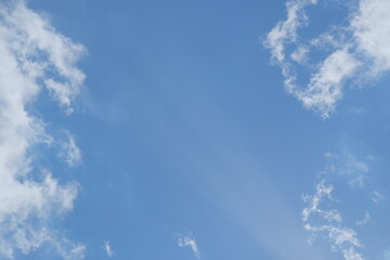 Clear blue sky with soft white clouds creating a serene atmosphere, ideal for backgrounds, designs, and inspirational themes, featuring ample copy space for text overlay