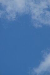 Clear blue sky with soft white clouds creating a serene atmosphere, ideal for backgrounds, design projects, or as a calming visual element with copy space