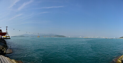 Panoramic view of a serene coastal scene with a pier, calm waters, and distant islands under a...