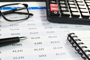 Closeup view of finance report with calculator and pen.