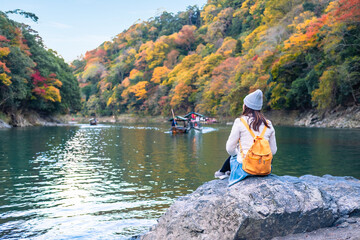 Young woman traveler relaxing and enjoy the beauty of autumn leaves at Arashiyama in Kyoto, Japan,...