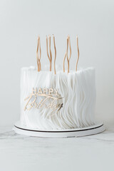Luxury birthday cake with white chocolate and fondant icing decorated with edible paper and golden...