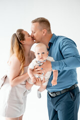 a young family with a small child, mom and dad with a newborn baby at home on the bed, smiling,...