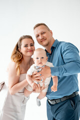 a young family with a small child, mom and dad with a newborn baby at home on the bed, smiling,...