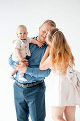 a young family with a small child, mom and dad with a newborn baby at home on the bed, smiling,...