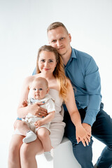 a young family with a small child, mom and dad with a newborn baby at home on the bed, smiling,...