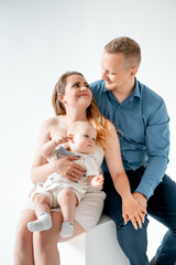 a young family with a small child, mom and dad with a newborn baby at home on the bed, smiling,...