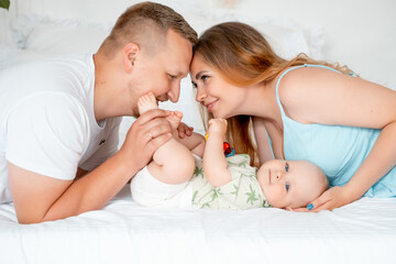 a young family with a small child, a mother and father with a newborn baby at home on the bed,...