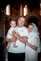 Christian family with a small child in the church, father, mother, and baby in the church, the...