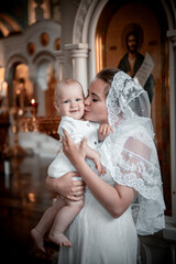 a mother with a small child in a church or cathedral, the baptism of a baby in a church, the...