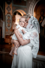 a mother with a small child in a church or cathedral, the baptism of a baby in a church, the...
