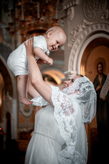 a mother with a small child in a church or cathedral, the baptism of a baby in a church, the...