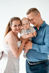a young family with a small child, mom and dad with a newborn baby at home on the bed, smiling,...