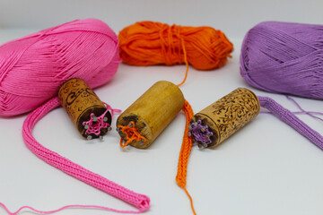 The process of knitting laces from cotton yarn in pink, purple and orange colors, on a light...
