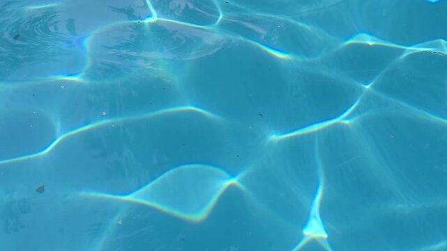 The water in the pool is blue, permeated with glitter and shimmer in the sun. Healthy lifestyle. Recreation for children.