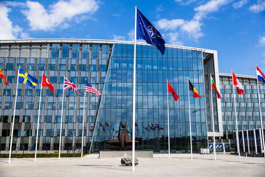 Exterior view of NATO headquarters in Brussels with member state flags displayed in front.