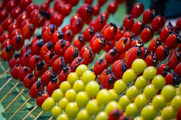 several colorful tanghulu are neatly arranged on a wooden stall