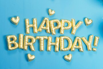 3D golden balloons spelling happy birthday on blue background