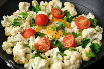 Delicious cauliflower cut into pieces and fried in a pan with red cherry tomatoes with parsley and...