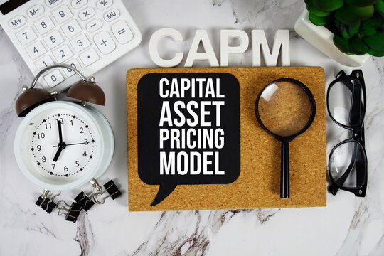 CAPM - Capital asset pricing model acronym with calculator, alarm clock and magnifying glass, business concept background