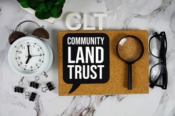CLT - Community Land Trust acronym with alarm clock and magnifying glass, communication concept...