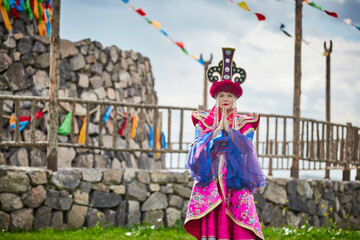 Naklejka premium Mongolian girls dressed in luxurious Mongolian costumes in front of an obo on the grassland