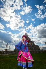 Fototapeta premium Mongolian girls dressed in luxurious Mongolian costumes in front of an obo on the grassland