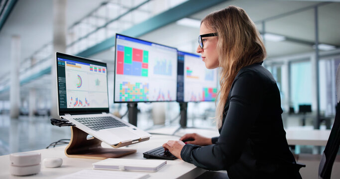 Young Woman In Office Using Computer To Analyze Business Data