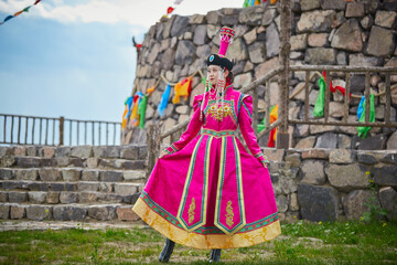 Mongolian girls dressed in luxurious Mongolian costumes in front of an obo on the grassland