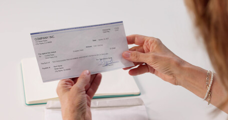 Woman Inserting Paycheck Envelope Into Laptop