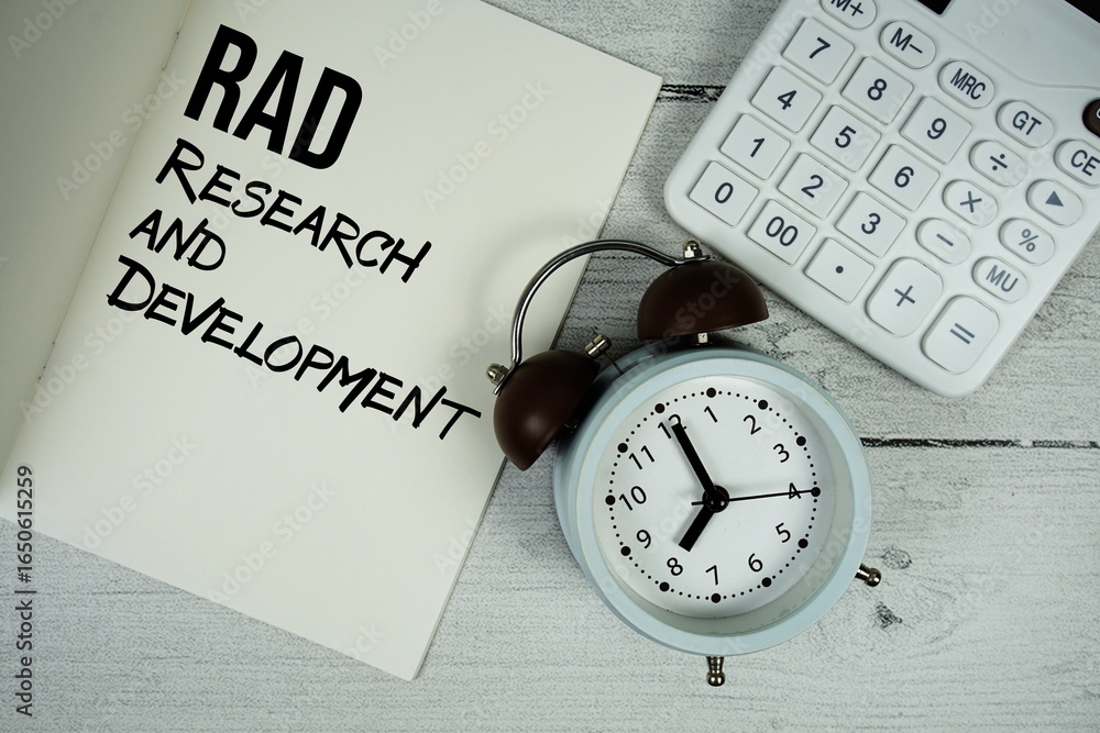 Poster research and development text on paper notebook page with alarm clock and calculator on wooden backg