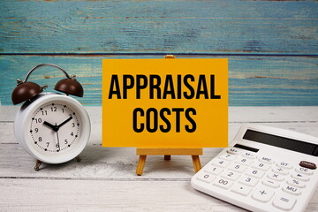 Appraisal Costs text written on paper card with calculator and alarm clock on wooden background