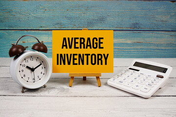 Average Inventory text written on paper card with calculator and alarm clock on wooden background