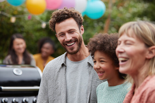 A happy, diverse family laughs together during an outdoor barbecue. Celebration, joy, and togetherness are evident. Perfect for family, lifestyle, or community themes.