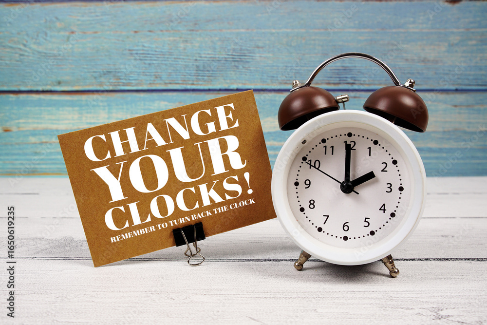 Poster change your clocks text written on paper card with alarm clock on wooden background