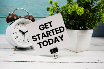 Get Started Today text written on paper card with alarm clock on wooden background