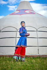 Mongolian girls dressed in luxurious Mongolian costumes in front of a yurt on the grassland