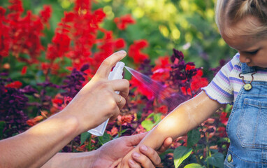 Dad sprays his child with mosquito repellent.